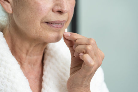 Closeup of an elderly woman taking a pill for a toothache, headache or stomach. Illness and disease...