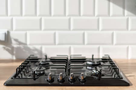 Modern kitchen interior design in white tones with stove closeup. Beautifully incident light in room. Household appliances concept. Place for cookingの写真素材