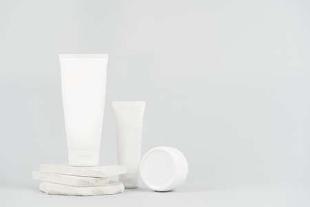Skin, body and hair care concept. White minimalist brand packaging mockup for shampoo, mask, hand and face cream in container and tube stand against light gray background with copy spaceの写真素材