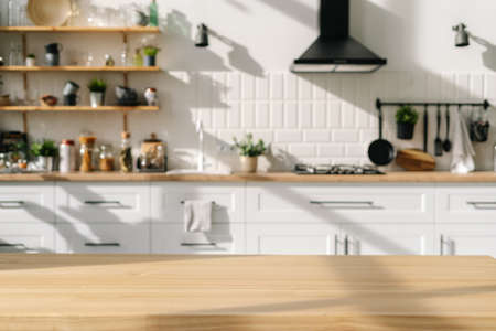 Scandinavian kitchen interior design with white furniture and diverse decorations. Wood stylish table in foreground. Household appliances. Bright dining room after repairの写真素材