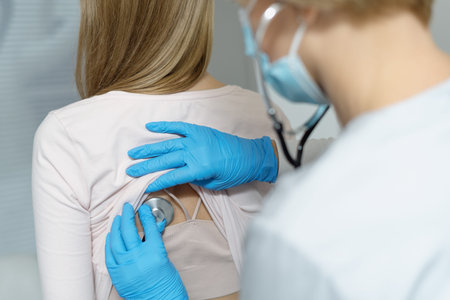 Back rear view of family doctor uses a stethoscope listening to a patient breathing and heartbeat....