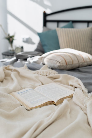 Home education, reading literature and weekend hobby concept. Vertical view of opened book, copybook or planner lying on bed in cozy bedroom with blurred copy space backgroundの写真素材