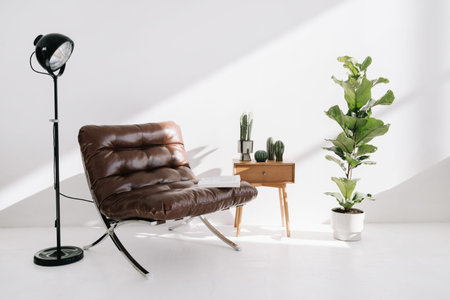 Armchair with open book standing near modern lamp light, side table, potted houseplants and home decor. Furniture and objects composition in apartment with contemporary interior designの写真素材