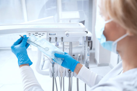 Portrait of dentist takes out instrument from packaging before patient's visit. Preparation for...