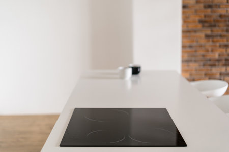 Closeup of black induction cooker in kitchen with brick wall. cup on background. House after renovation. Appliances and household equipment. home comfortの写真素材
