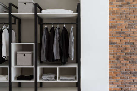 Cropped side view of personal dressing room with clothes hanging on racks. Contemporary room interior design in loft style. fashionable clothesの写真素材