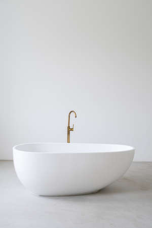 Vertical shot of classic porcelain bathtub in empty room. Bathroom in bright apartment with contemporary interior, copy space on background. Advertising concept of new tubの写真素材