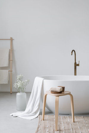 Cropped view of ceramic white bathtub with decor in modern bathroom interior design. home spa...