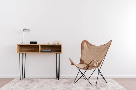 Lamp, open book and music column standing on wood table near armchair. Contemporary room design....