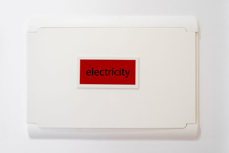 Closed electricity meter hanging on white wall in residential building. Usage of power switch panel....