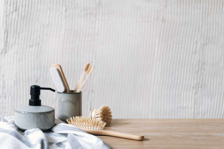 Morning routine concepts. Close up view of ceramic cup with toothbrush on wooden shelf in bathroom with soap dispenser, towel and hair brush. Personal accessories for self care against copy space wallの写真素材