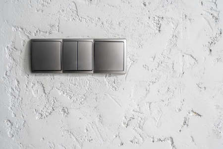 Cropped view of gray light switches on textured wall in modern apartment after renovation. energy saving. Safety and comfort concept. Minimalist house interior designの写真素材