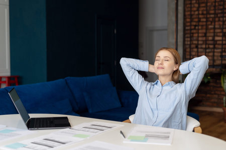Portrait of happy woman resting during hard work. Person closing eyes while relaxing in home office. Break from work time. Stress free employeeの写真素材