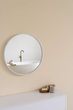 Side view of bath accessories on chest of drawers. Bath tub reflection in mirror. home spa. beauty elements. Modern bathroom interior design in beige tonesの写真素材
