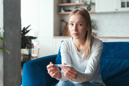 Portrait of surprised woman with her pregnancy test in hands. unintended pregnancy. Sick lady with...