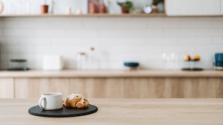 Croissant and coffee on kitchen countertop, against blurred minimalist interior with modern...