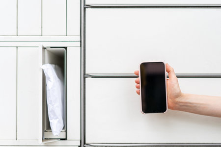 Client hold smartphone with copy space display near cell of automatic post terminal outdoors....