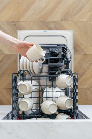 High above view of person putting dirty dishes in open dishwasher. contemporary kitchen appliances. home comfort. Concept of cleanliness. Kitchen interior design details. washing kitchenwareの写真素材