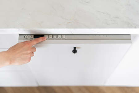 High above view of person choosing eco mode on control panel of dishwasher. Cleansing dishes. contemporary kitchen appliances. home comfort. Concept of cleanliness. Kitchen interior design detailsの写真素材