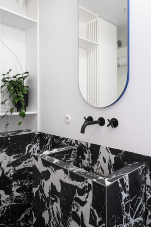 luxury interior design in hotel bathroom with modern wash basin, water dark faucet, black and white marble tile and mirror on wall indoorsの写真素材