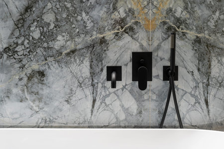 closeup of detail interior design in apartment bathroom with modern black water tap, shower head and...