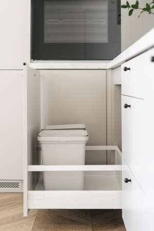 Segregated household garbage. Recycling bins install into a modern kitchen cupboard with white drawer for set of different trash can. Concept of caring for the environmentの写真素材