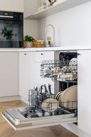 Open dishwasher with clean dishes, cups and cutlery after washing. modern kitchen appliances. Concept of cleanliness. Contemporary kitchen interior design Scandinavian styleの写真素材