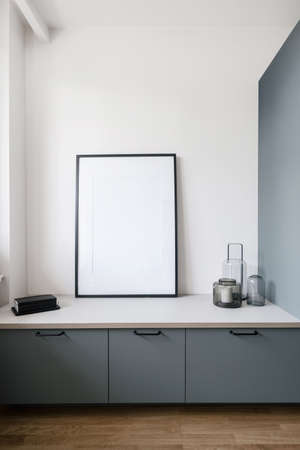 interior design in living room with gray cupboard, candle in glass jar on white countertop and mockup picture on wall in contemporary apartmentの写真素材