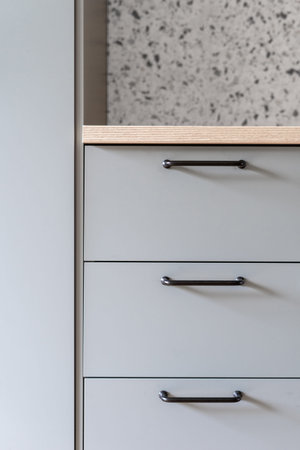 closeup of modern kitchen furniture or gray drawers with dark metal handles and wooden countertop in apartmentの写真素材