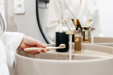 Concept of oral and dental care at home. Cropped shot of woman holding bamboo toothbrush with...