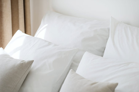 Part of comfortable bedroom with hypoallergenic pillows in white and clean pillowcases on bed. Hotel...