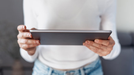 cropped shot of female hands hold portable digital tablet device with gray back side, reading or communicate online at home, networking conceptの写真素材