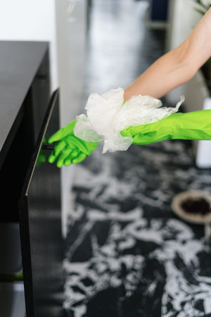 female hands in rubber gloves open wooden cupboard door and putting plastic bag in bin bucket,...