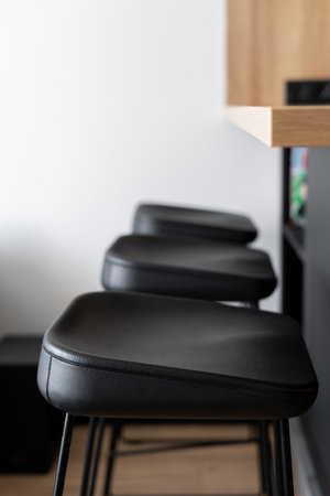 detail in kitchen interior with modern style, closeup of leather counter stools in black color near wooden countertop, vertical shotの写真素材