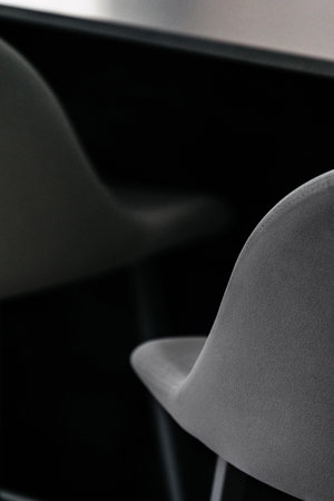 selective focus on back of soft chair with gray textile upholstery near table at room with modern interior, home office workplace conceptの写真素材