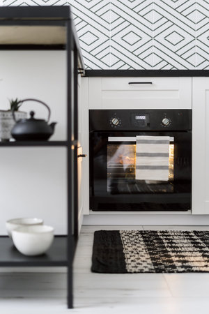 homemade baking, selective focus on electric oven with fresh pastry inside at kitchen with stylish...