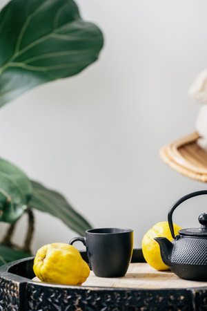 still life composition, Chinese teapot with brewing beverage, ceramic mug and healthy fresh fruits on wooden side table near houseplant on white backgroundの写真素材