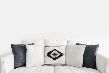 front view on comfort sofa with cushions in textile covers on white background with copy space, home decor idea for bohemian design in interiorの写真素材