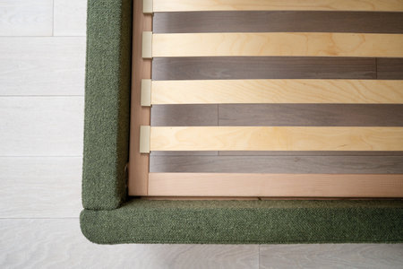 top view of wooden base with lamellas in modern bed with green upholstery in bedroom, closeupの写真素材