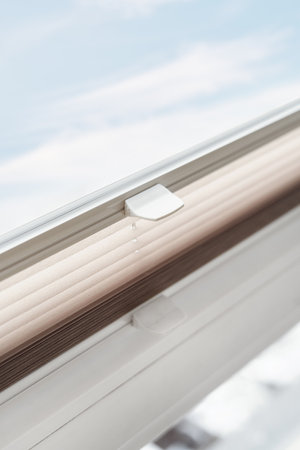 plastic handle on pleated blind jalousie on window in living room, modern and comfort mechanism of controlling lighting range, protection from sunlightの写真素材