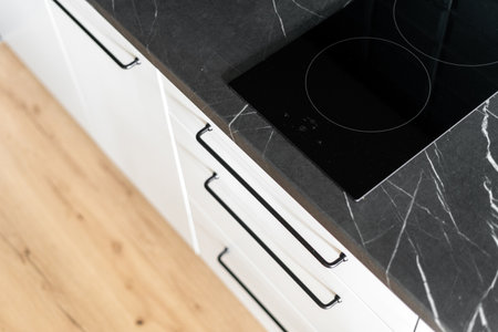 top view of glass ceramic induction hob with control panel on marble countertop at kitchen with modern interior and white furniture cabinet, household appliances conceptの写真素材