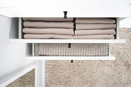 top view of clean bath towels neatly folded in drawers of modern wooden wardrobe in room, organized space concept, order inside closetの写真素材