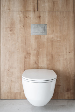 front view on white wc bowl with concealed cistern and water flush button switch on wall in luxury bathroom at apartment or hotel room. interior design conceptsの写真素材