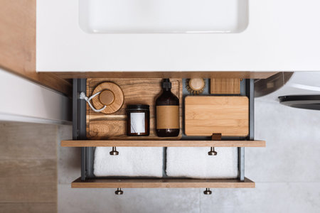 top view of open drawers of cupboard with neatly folded clean towels, bamboo storage basket,...