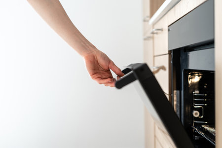 Cropped view of housewife using microwave, opening glass door on electric oven, cooking food at home. Concept of household appliance, baking equipment at kitchenの写真素材