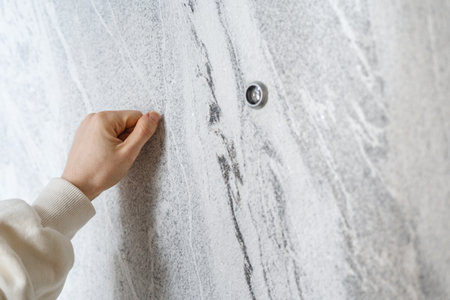 Selective focus on woman hand knocking on the grey door standing in the doorway. Delivery person, salesperson, hotel service or neighbor wants to come in to houseの写真素材