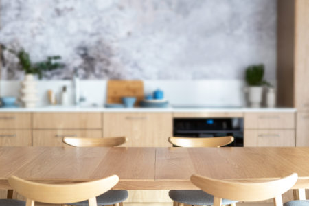 empty dining table and chairs on blurred kitchen background, modern wooden furniture at stylish...
