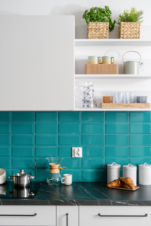 stylish interior at kitchen, saucepan on induction glass ceramic hob, metal storage jars with lids...