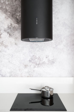 detail at kitchen with contemporary interior, black hood extractor and induction glass ceramic stove with saucepan on grey wall backgroundの写真素材