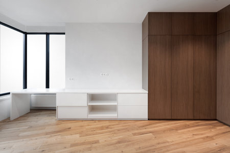 empty living room with wooden closet and workspace. wooden laminate floor, white wall and window in contemporary apartment after renovationの写真素材